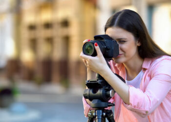 Professional female photographer focusing camera objective, photo shooting