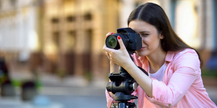 Professional female photographer focusing camera objective, photo shooting