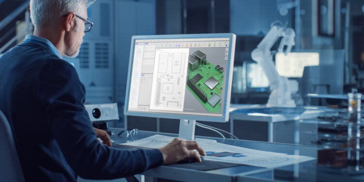 Engineer Works on Computer Uses CAD Software to Design 3D Industrial Machinery Component. In the Background Robot Arm Concept Standing in Heavy Industry Engineering Facility. Over the Shoulder Shot